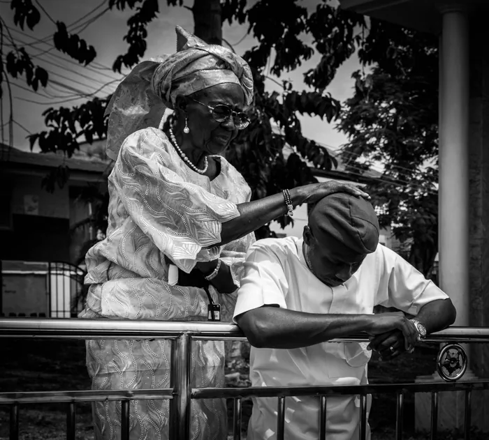 An elder places her hand on Ayobami's head in blessing